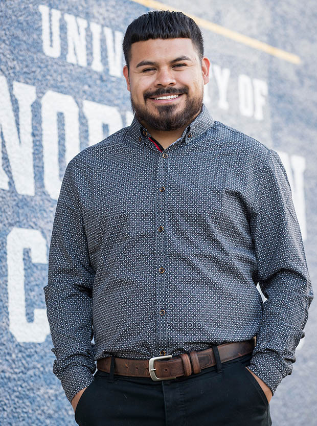 Fernando Beltran standing next to a painted University of Northern Colorado logo.