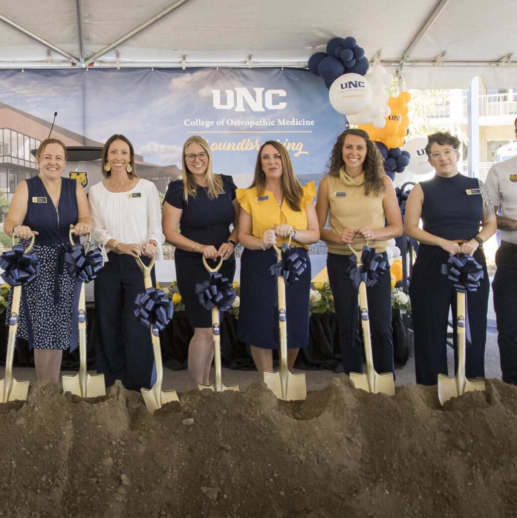 University Advancement team standing with gold shovels behind a pile of dirt