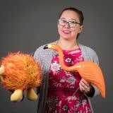 A headshot of Chelsie Romulo holding a flamingo