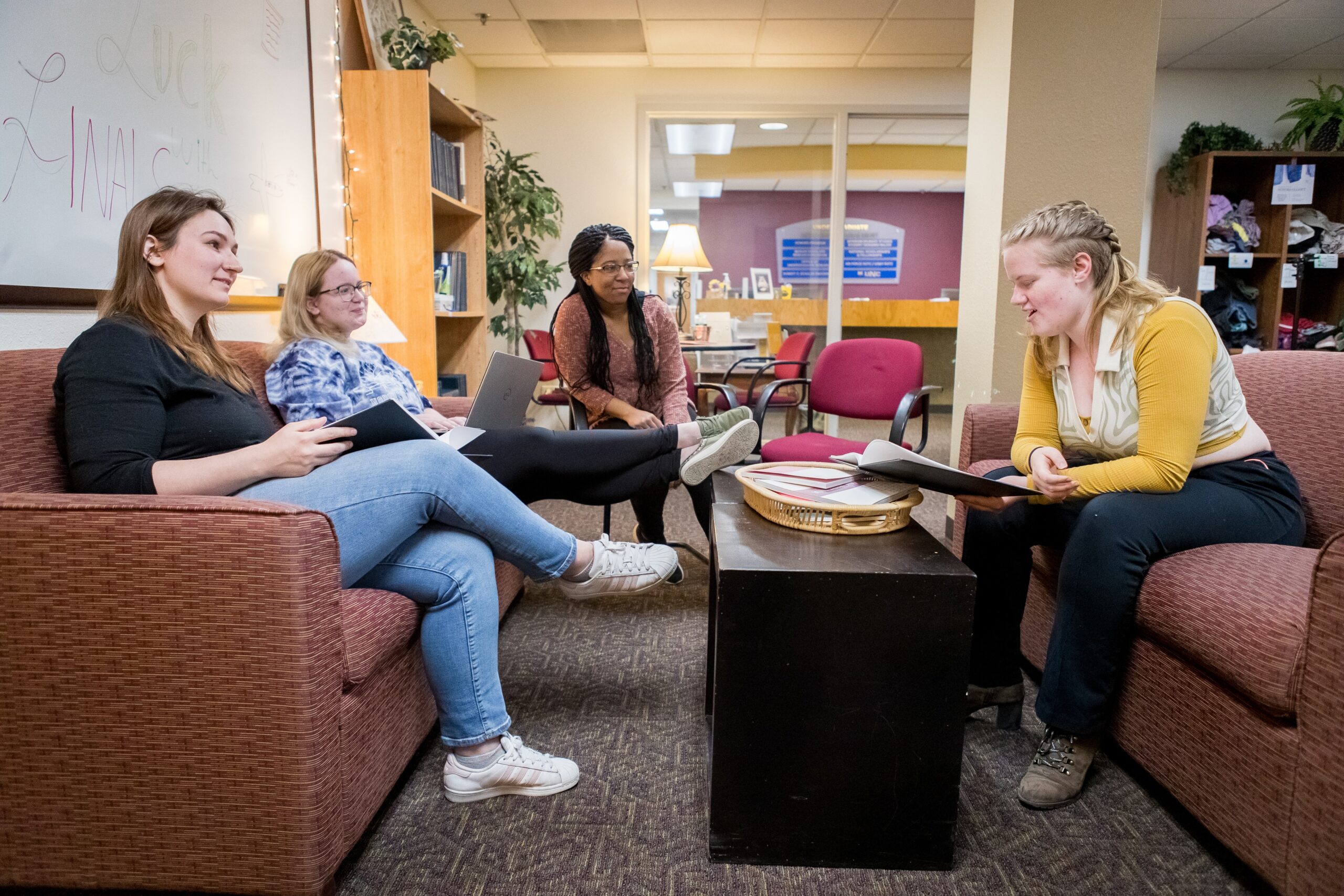 Four students sitting around couches discussing