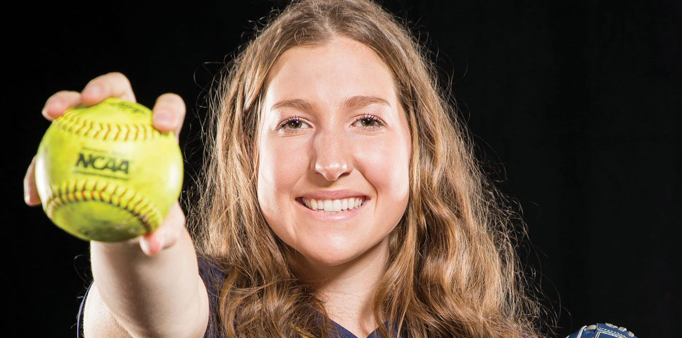 Erin Caviness holding a yellow softball in her hand and smiling