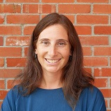 A headshot of Lauryn Benedict against a brick wall