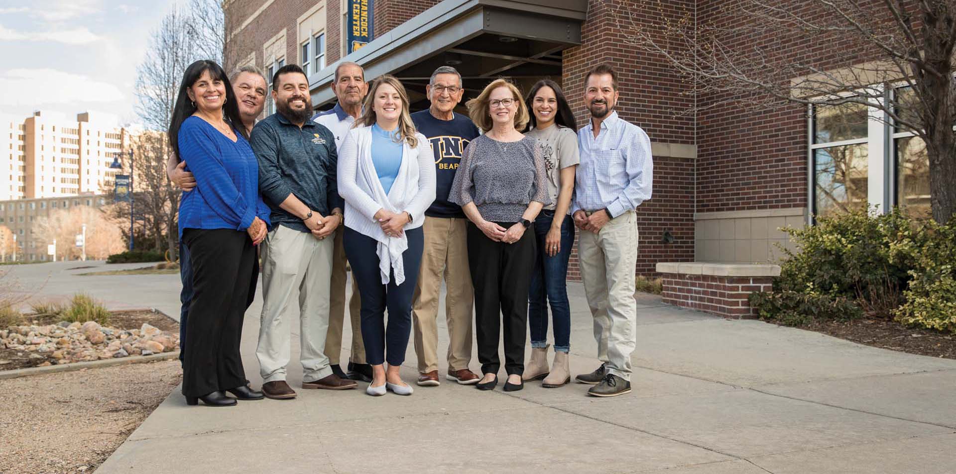 Nine family members standing next to each other and smiling outside of a building