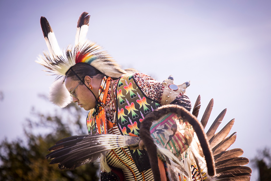 A native American man wears a traditional native American outfit.