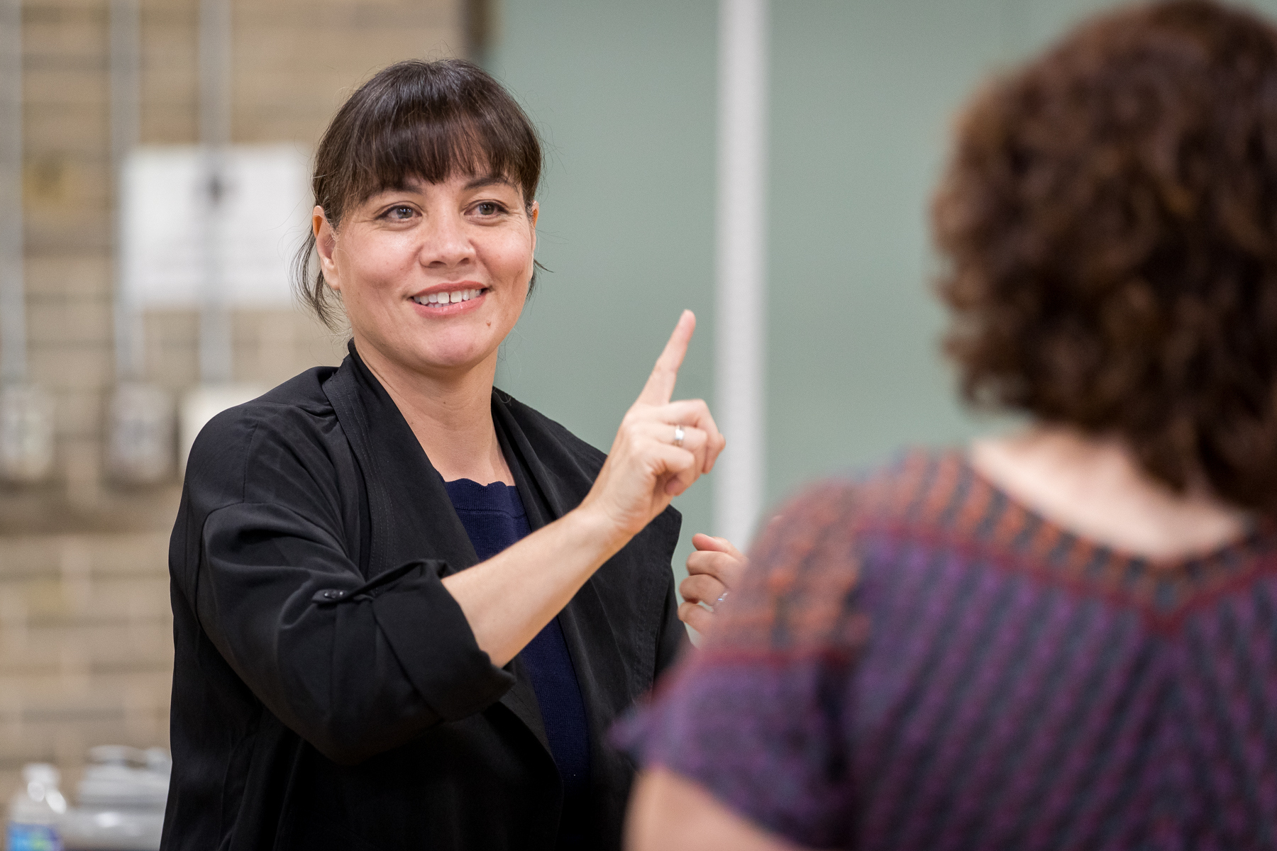 Teacher using American Sign Language to communicate with a student, smiling and engaged in conversation.