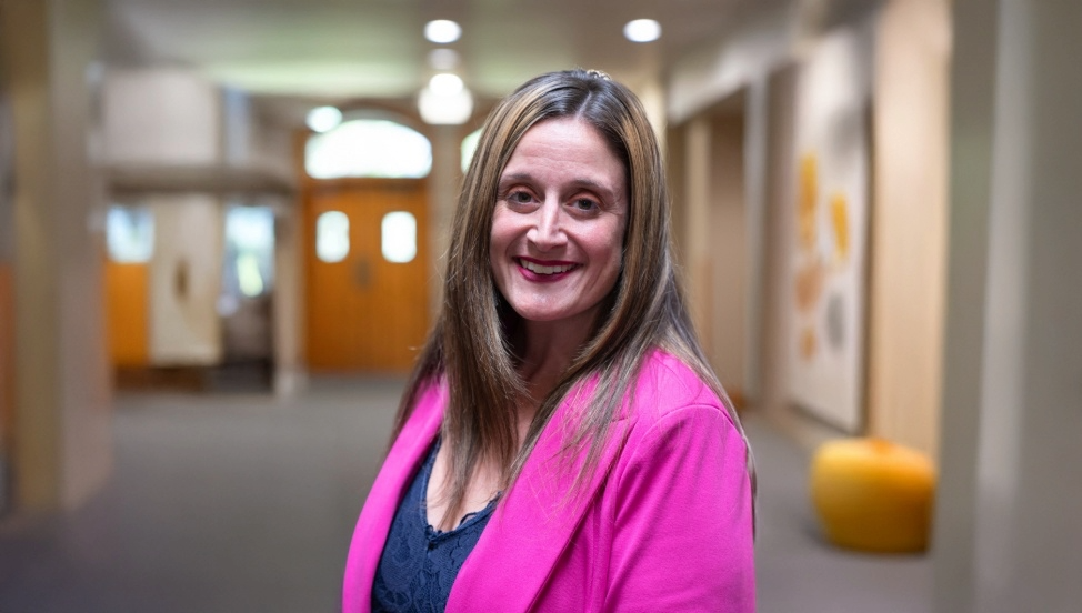 Headshot of Amanda Schroeder in a pink blazer with a hallway background