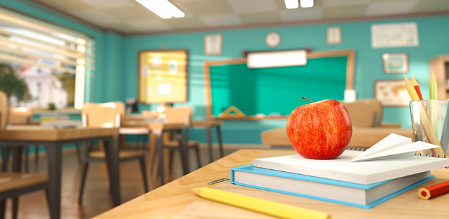 An apple on top of books on a desk in a classroom
