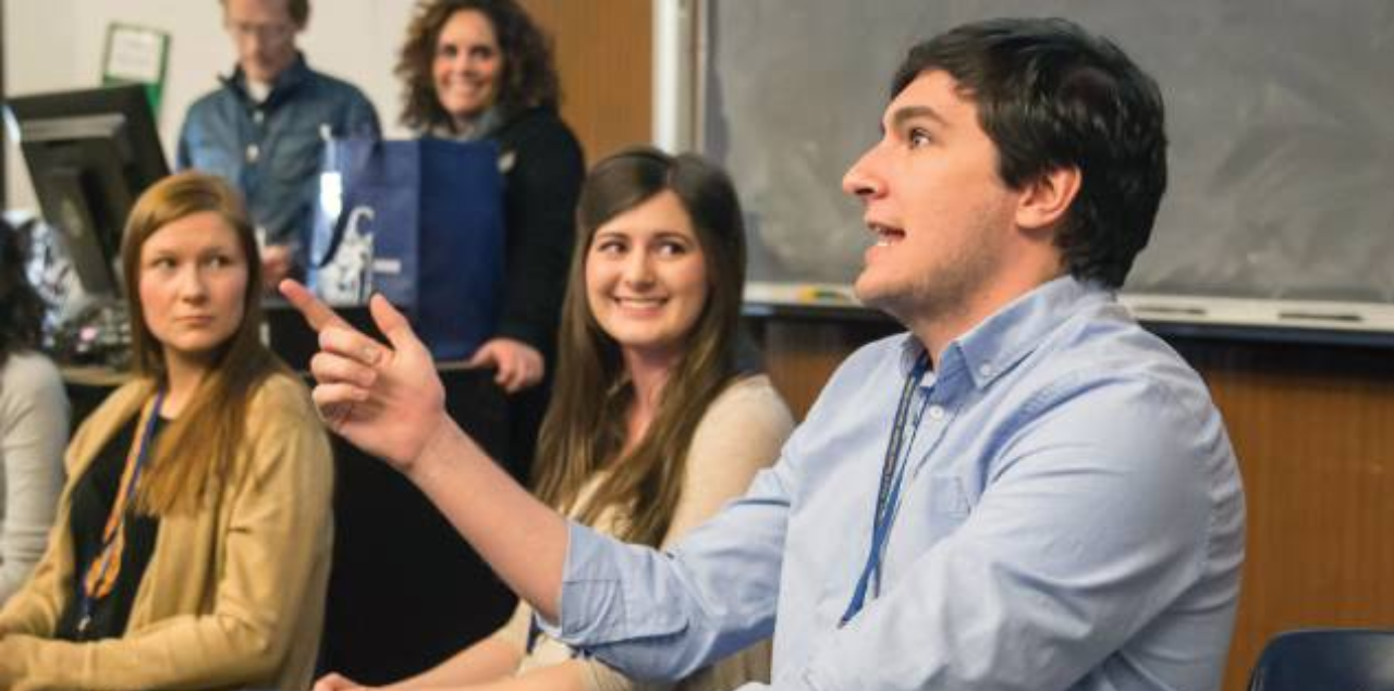 A man speaking to a classroom while students look on.