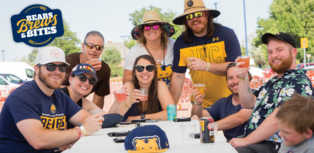 A group of people at a table holding up beers