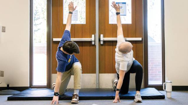 A student worker doing an excersise along with a cancer rehab patient