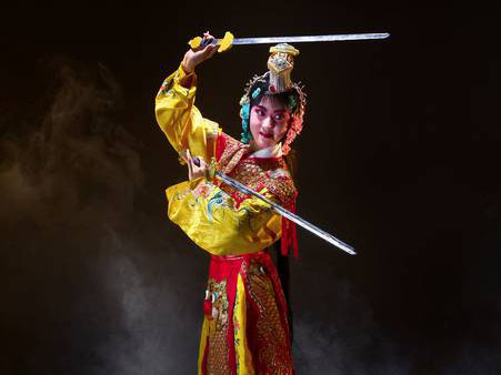 Woman holding swords wearing a red and yellow Hanfu with floral embellishments.