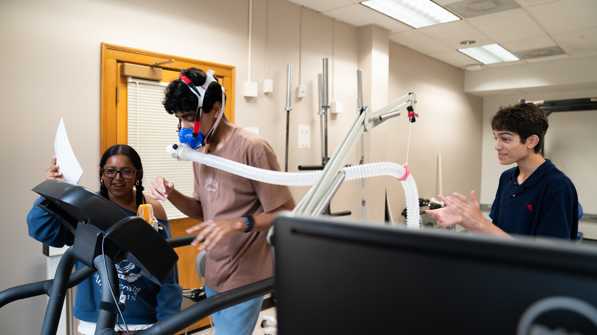 Students running a O2 test by looking at statistics on another student running on treadmill
