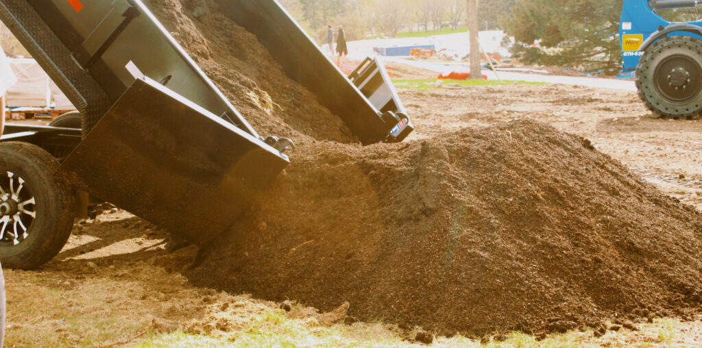 A truck dropping down a pile of compost soil