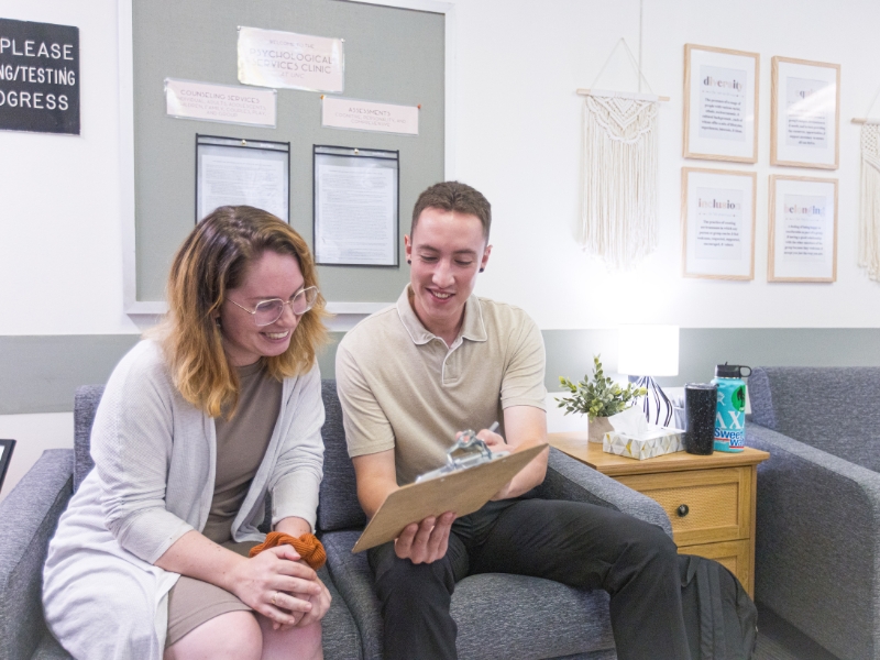 Two graduate counseling students working together on client forms during a counseling session.