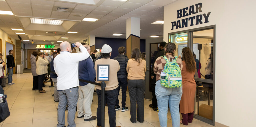 A crowd of people standing in front a Bear Pantry sign