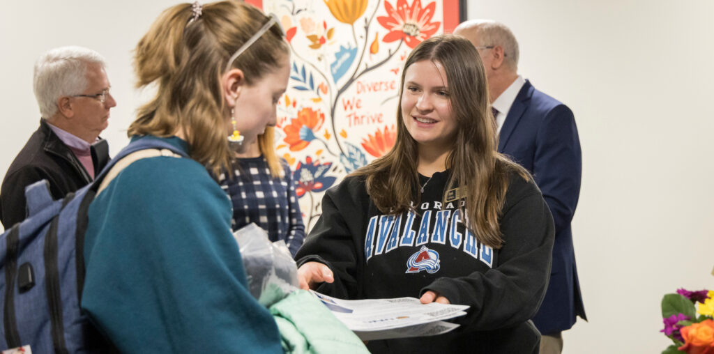 A student talking to another student pointing at a clipboard