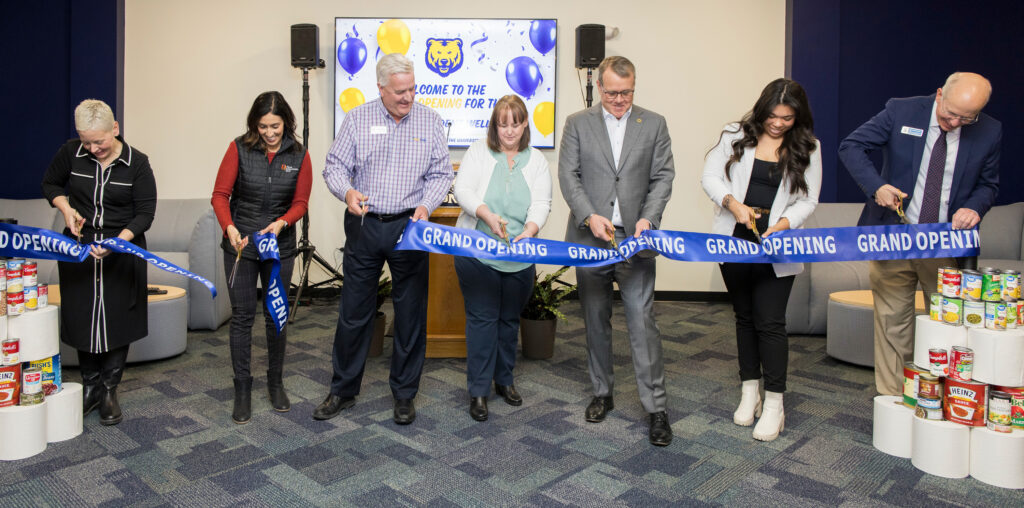 A line of people cutting a large blue ribbon