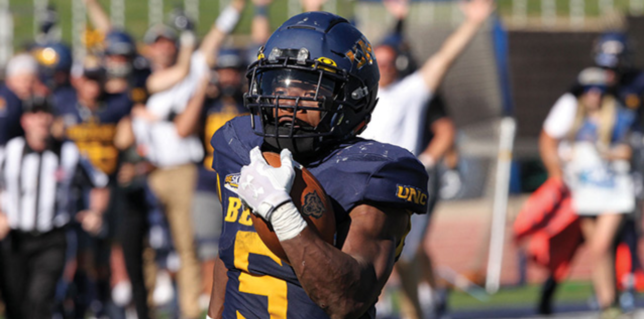Student athlete Elijah Dotson in full football gear, holding a football