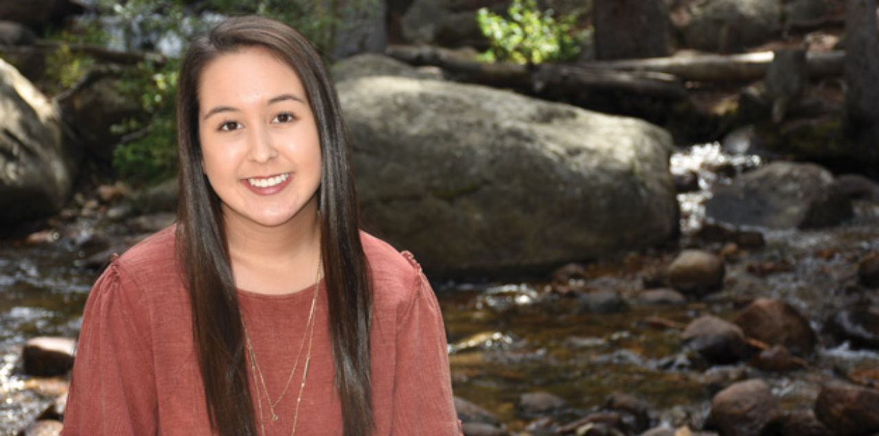 UNC student Emily Reid sitting next to a rocky stream outdoors.