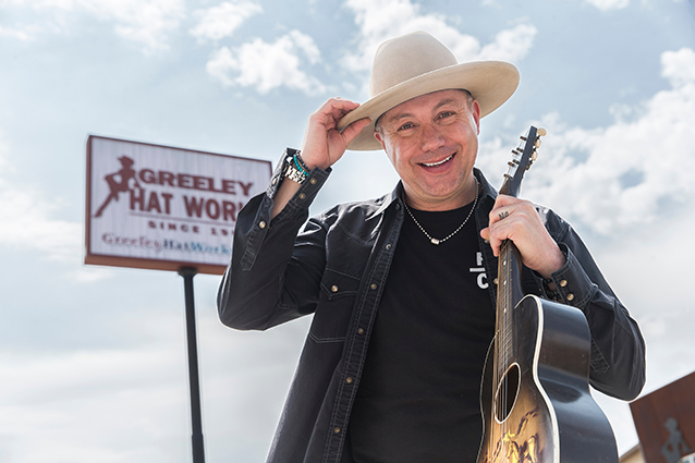 Trent Johnson holding his hat and a guitar