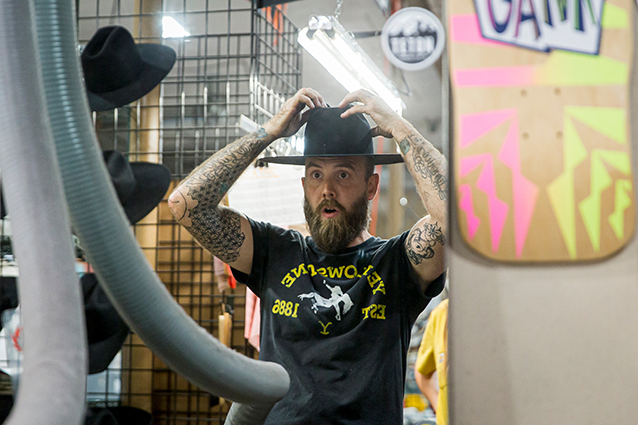 A man looking at himself in the mirror wearing a cowboy hat