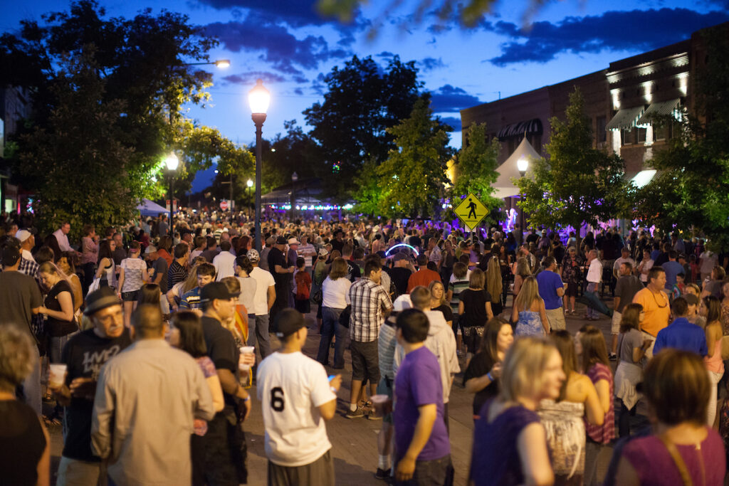 A large crowd walking around the street in Greeley at night