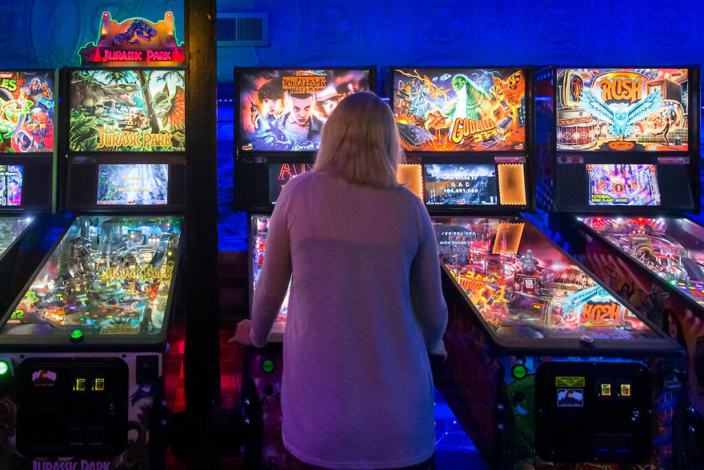 the back of a person playing pinball