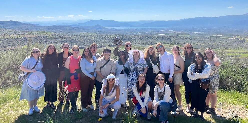 A group of people pose in front of a large landscape.