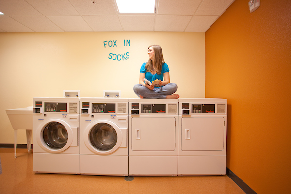 A student sits on top of a washing machine.