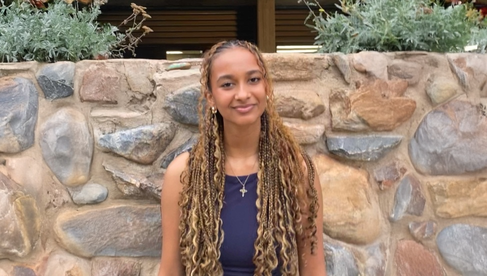 Headshot of Milaat in front of a stone wall
