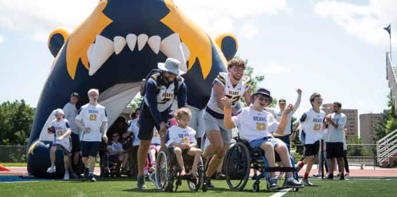 UNC football players taking to the field alongside students from the No Limits camp.