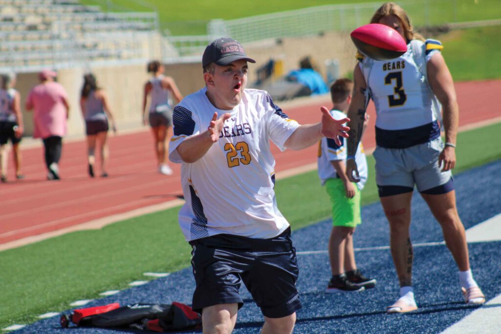 A camp participant reaching out his arms to catch a football.