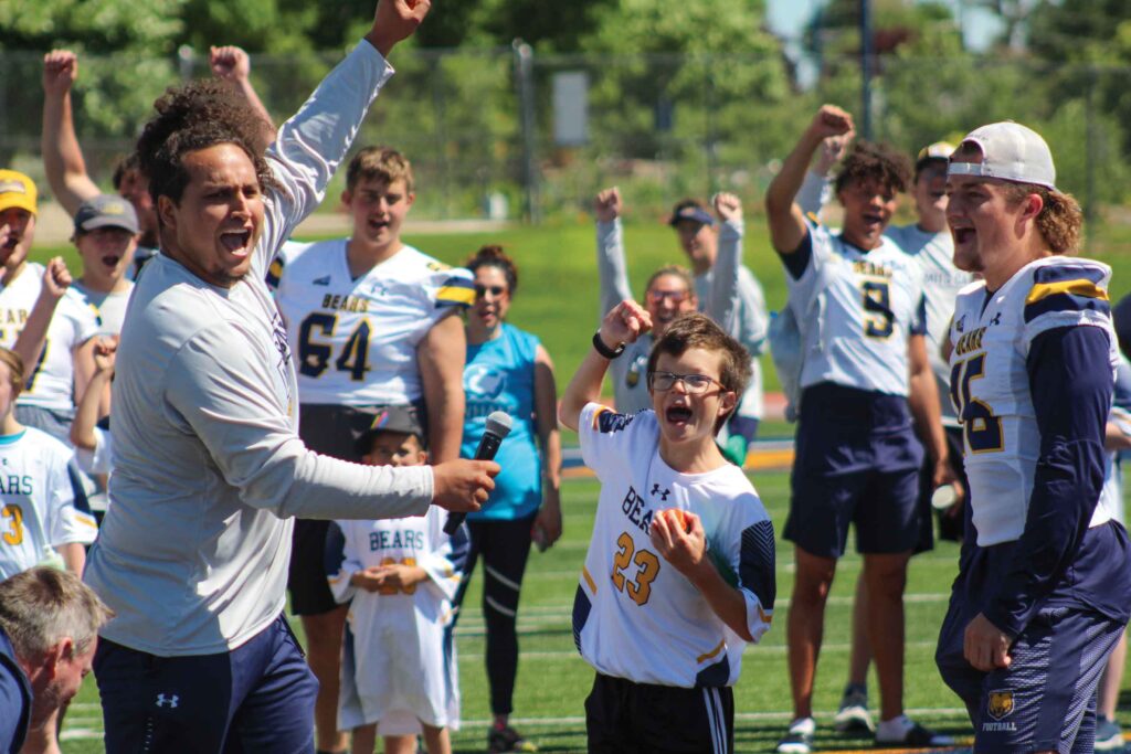 A group of camp participants cheering on the field.