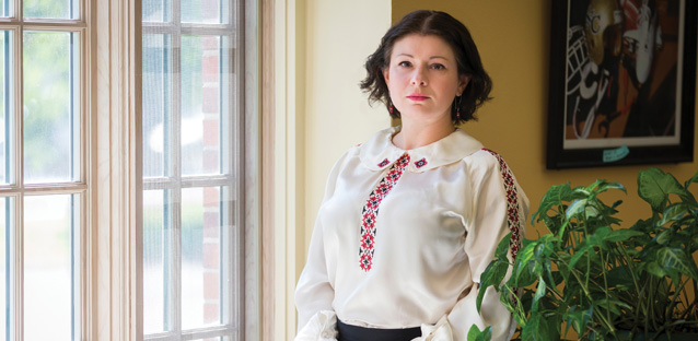 Olga Baron standing near a window looking at the camera