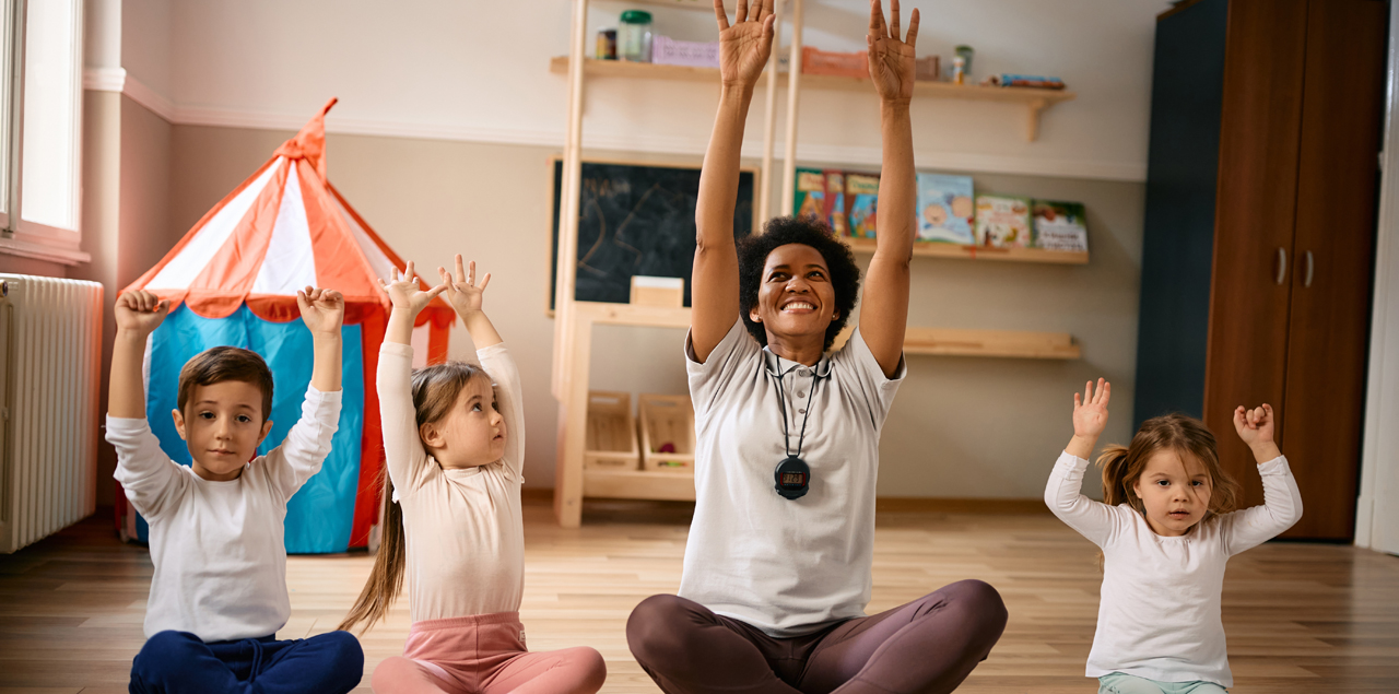 Happy preschool teacher and group of kids stretching during class.