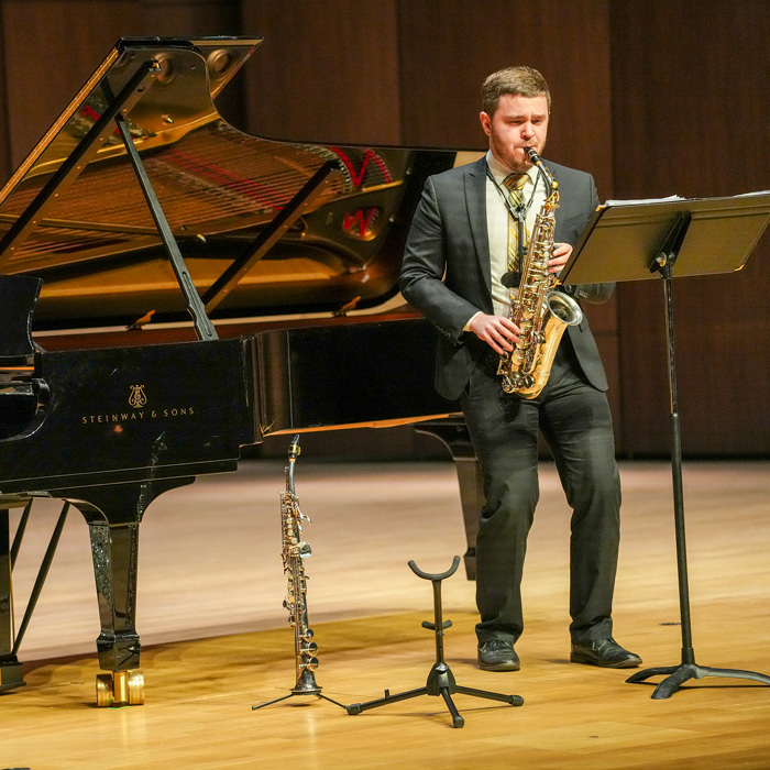 Taylor Gilman playing saxophone on stage in Campus Commons Performance Hall during the PVA Spotlight event.