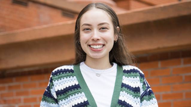 UNC student Sage Pennethy smiling at the camera in front of a brick building.