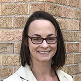 A headshot of Sharon Bywater-Reyes up against a brick wall