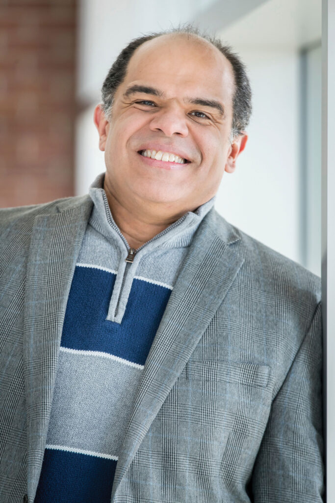 A man in a grey suit smiling at the camera.