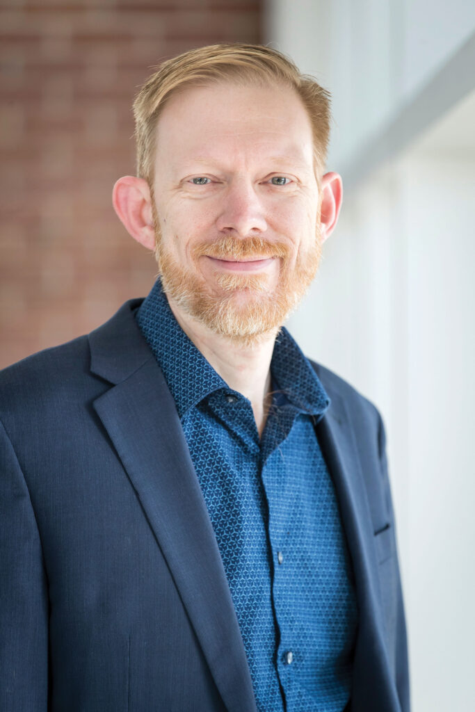 A man in a blue suit smiling at the camera.