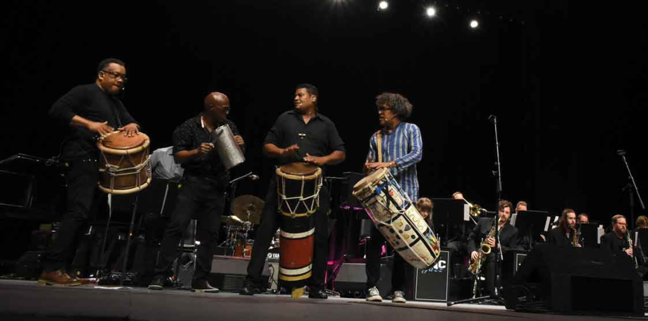 A group of students playing percussion instruments on stage.