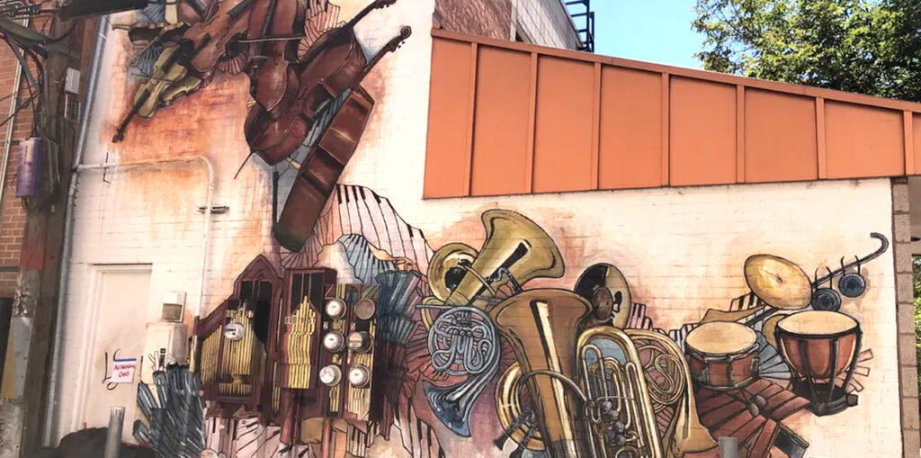 A mural of a variety of instruments painted on the back of a building.