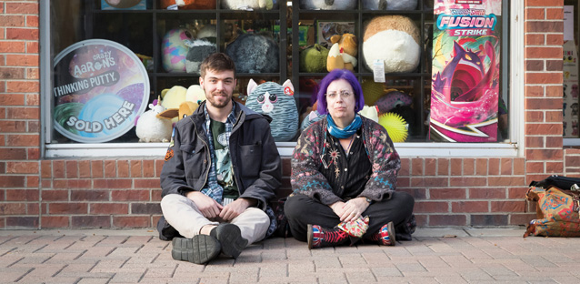 UNC alumnus Colin McGuire sitting on the ground next to Professor of English Tracey Sedinger