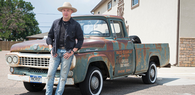 Trent Johnson leaning on a truck wearing a cowboy hat