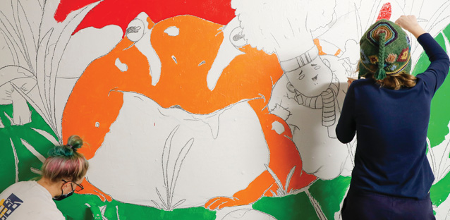 A student painting a mural on the walls of a tunnel