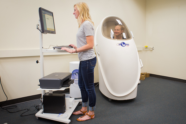 Graduate students operating a body nutritional analysis machine known as a bod pod.