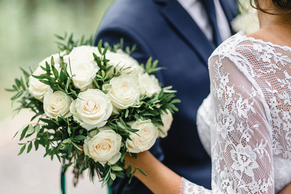 Bride holds flowers, hugs groom