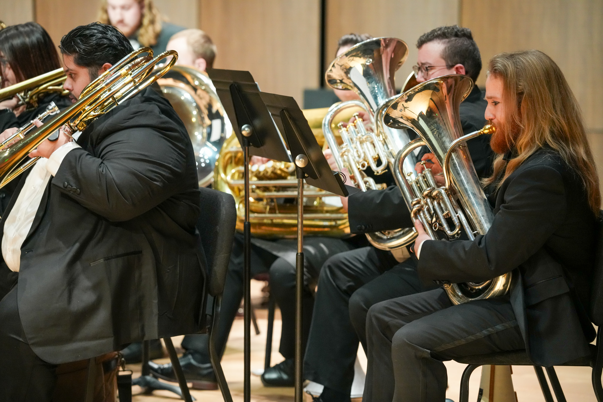 Low brass section performing on stage in UNC Wind Ensemble.