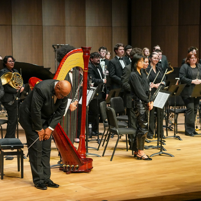 UNC Wind Ensemble receiving applause on stage in Campus Commons Performance Hall.