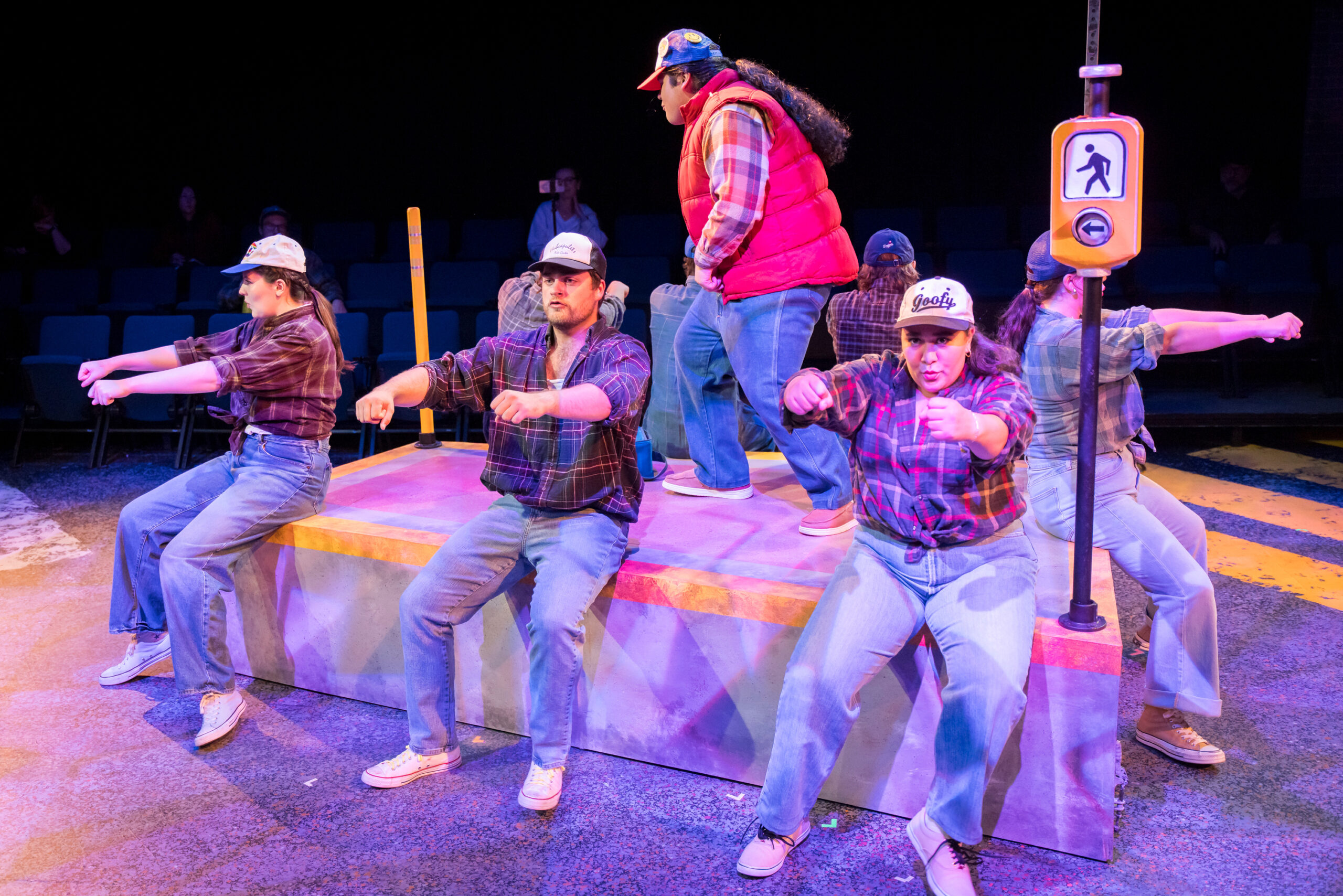 5 characters pretending to drive a truck on stage in Working: A Musical.